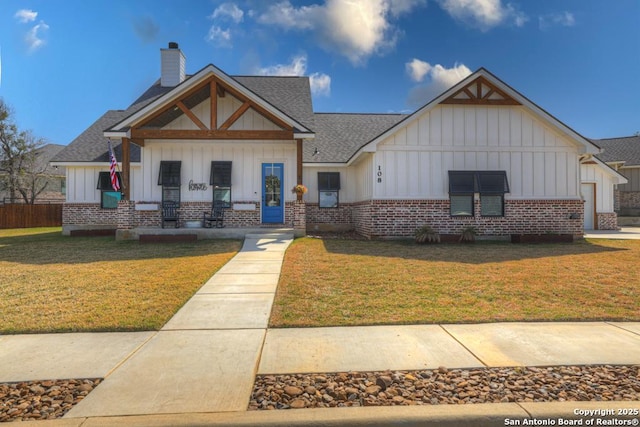 view of front of property with a chimney, brick siding, board and batten siding, and a front lawn