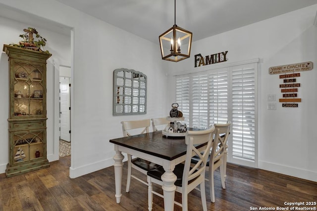 dining area featuring baseboards, a notable chandelier, and wood finished floors