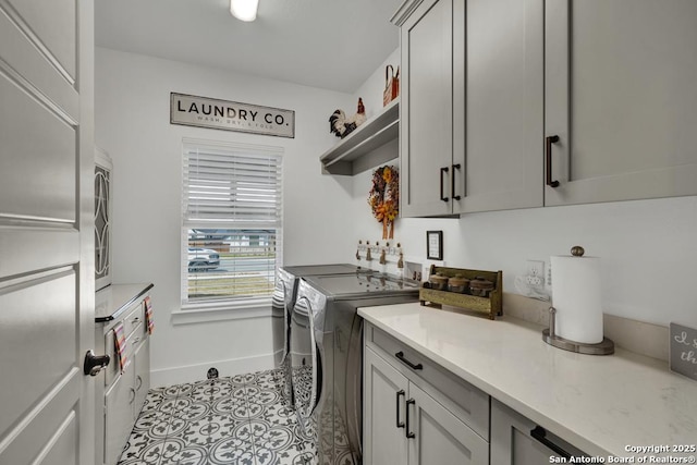 washroom with washing machine and dryer, light tile patterned flooring, cabinet space, and baseboards