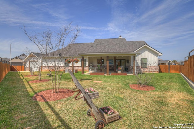 back of house featuring roof with shingles, a yard, a fenced backyard, a patio area, and brick siding