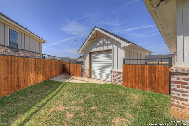 view of yard with a garage, fence private yard, and an outdoor structure