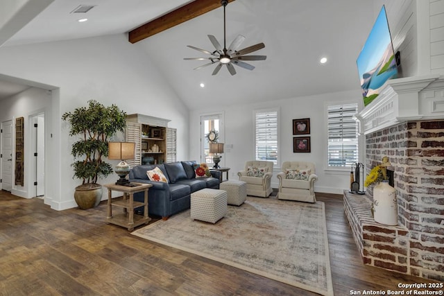 living room with visible vents, beamed ceiling, dark wood-style floors, a brick fireplace, and ceiling fan