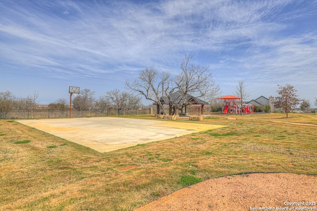 view of basketball court with playground community, a lawn, community basketball court, and fence