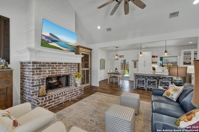 living room with visible vents, a fireplace, high vaulted ceiling, and wood finished floors