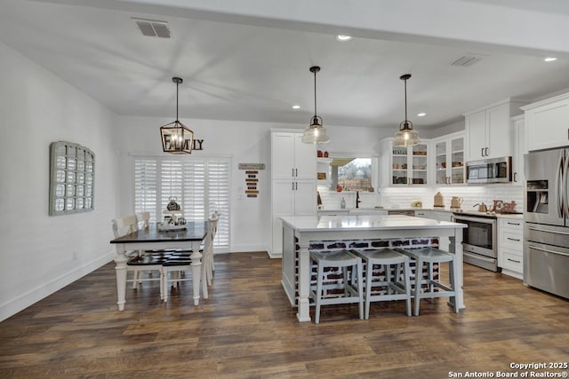 kitchen featuring visible vents, white cabinets, stainless steel appliances, and decorative backsplash