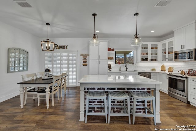 kitchen with tasteful backsplash, visible vents, appliances with stainless steel finishes, and a kitchen breakfast bar