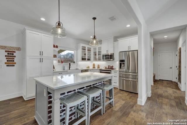 kitchen with white cabinetry, a kitchen breakfast bar, backsplash, and stainless steel appliances