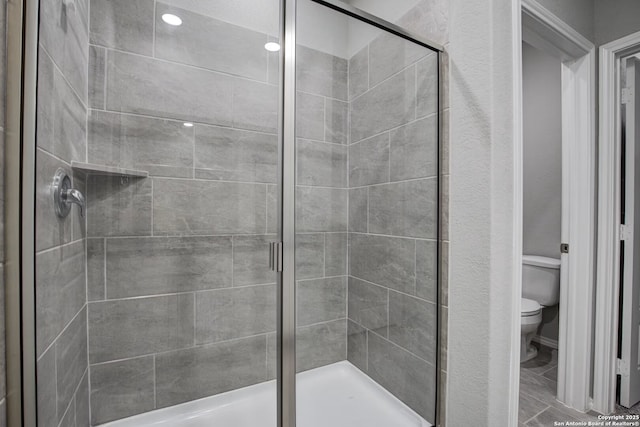 bathroom featuring a shower stall and toilet