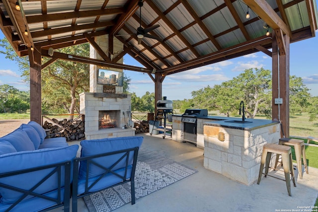 view of patio featuring an outdoor living space with a fireplace, a gazebo, area for grilling, an outdoor kitchen, and a sink