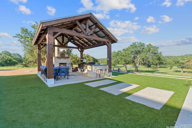 view of yard featuring outdoor dry bar, exterior kitchen, a gazebo, an outdoor stone fireplace, and a patio