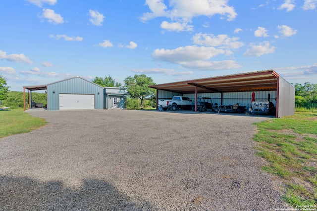 view of car parking with a detached garage and an outbuilding