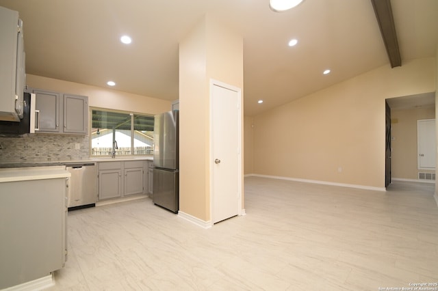 kitchen featuring backsplash, vaulted ceiling with beams, gray cabinets, stainless steel appliances, and a sink