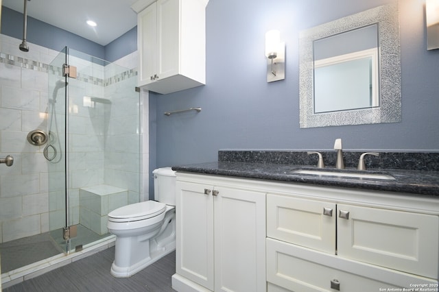 bathroom featuring vanity, a shower stall, and toilet