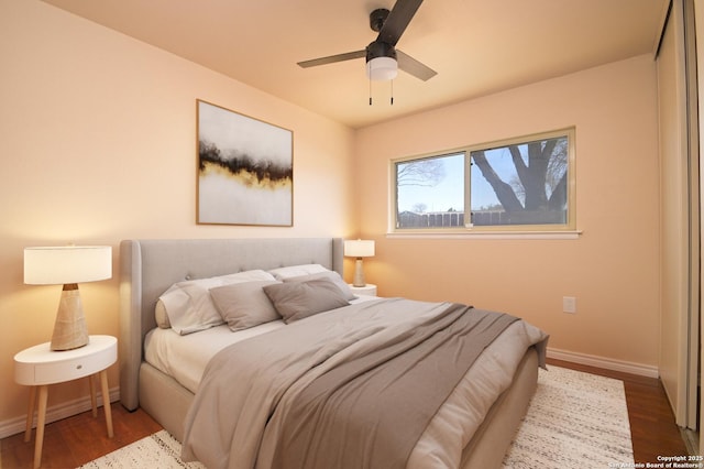 bedroom with ceiling fan, baseboards, and wood finished floors