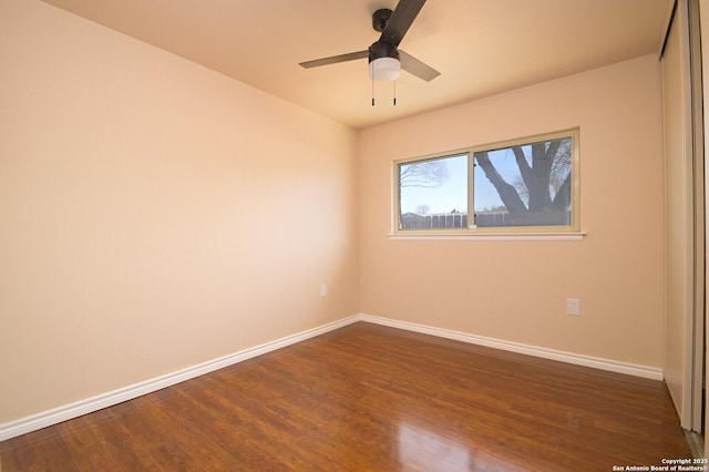 empty room featuring ceiling fan, baseboards, and dark wood finished floors