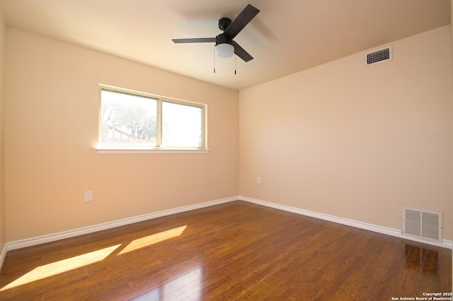 unfurnished room featuring dark wood-style floors, visible vents, a ceiling fan, and baseboards