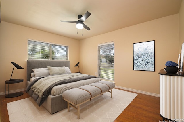 bedroom with a ceiling fan, wood finished floors, and baseboards