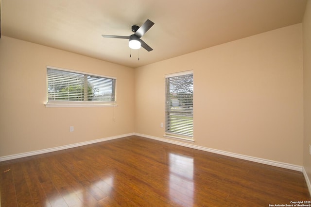 empty room with plenty of natural light, ceiling fan, baseboards, and dark wood-style flooring