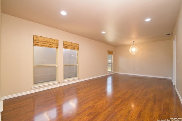 unfurnished room with wood finished floors, visible vents, baseboards, an inviting chandelier, and recessed lighting