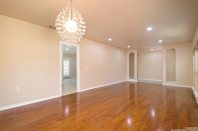 unfurnished room featuring baseboards, recessed lighting, arched walkways, a notable chandelier, and wood-type flooring