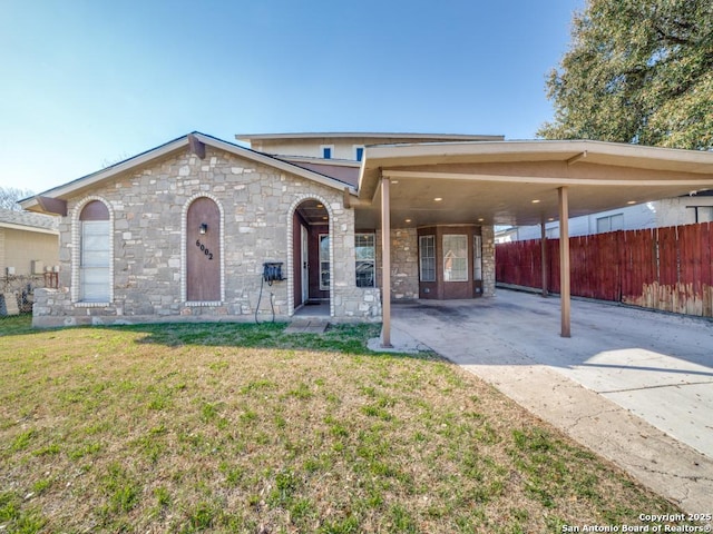 view of front of home with an attached carport, a front yard, and fence