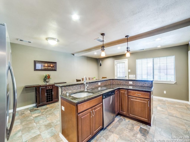 kitchen with a sink, appliances with stainless steel finishes, a kitchen island with sink, and brown cabinetry