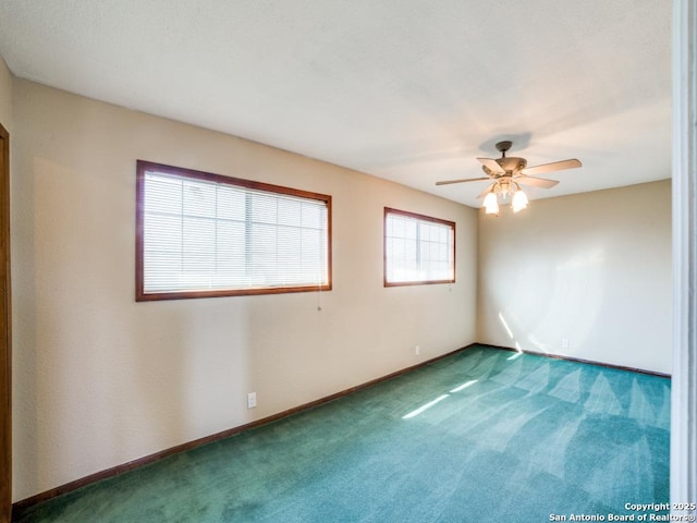 carpeted empty room featuring a ceiling fan and baseboards