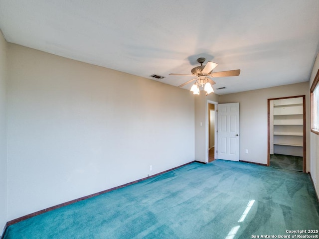 unfurnished bedroom with visible vents, a walk in closet, a ceiling fan, carpet flooring, and baseboards