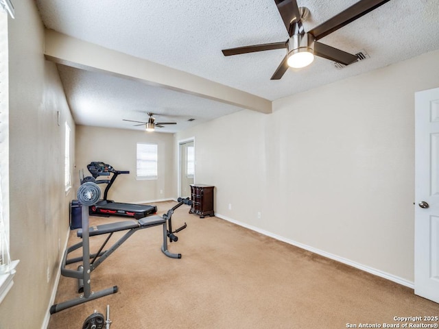 exercise area featuring visible vents, baseboards, carpet, a textured ceiling, and a ceiling fan