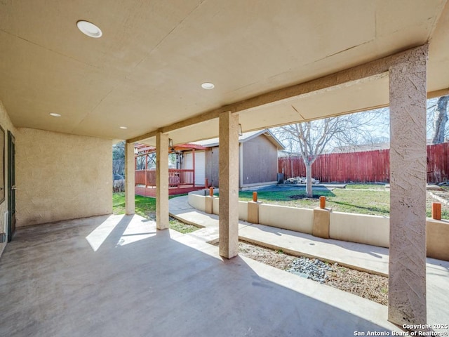 view of patio with a storage unit, an outbuilding, and fence