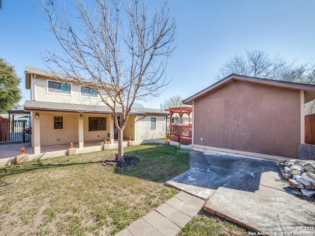 back of property with fence, a pergola, stucco siding, a patio area, and a lawn