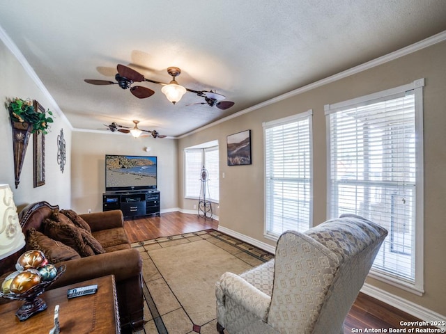 living area with a ceiling fan, a textured ceiling, wood finished floors, crown molding, and baseboards