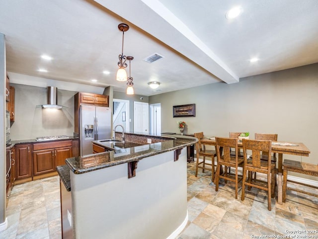 kitchen featuring visible vents, brown cabinets, an island with sink, a sink, and stainless steel appliances