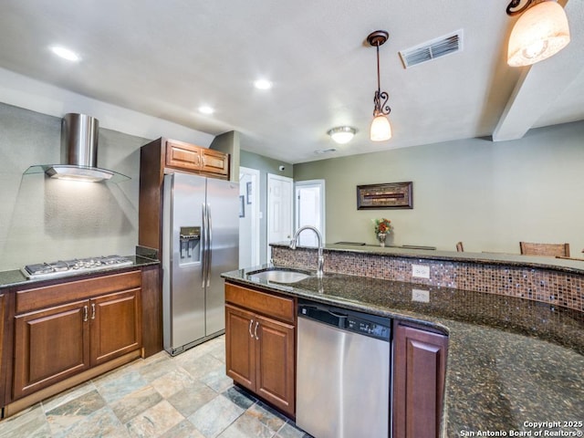 kitchen with visible vents, wall chimney range hood, appliances with stainless steel finishes, hanging light fixtures, and a sink