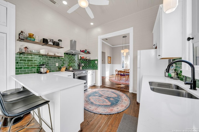 kitchen featuring range hood, visible vents, stainless steel range with gas stovetop, a sink, and white cabinetry