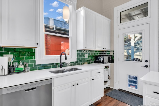 kitchen featuring backsplash, dark wood-style flooring, stainless steel dishwasher, white cabinets, and a sink