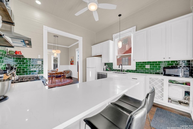 kitchen with freestanding refrigerator, a sink, light countertops, white cabinets, and a kitchen bar