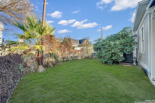 view of yard with central AC and fence