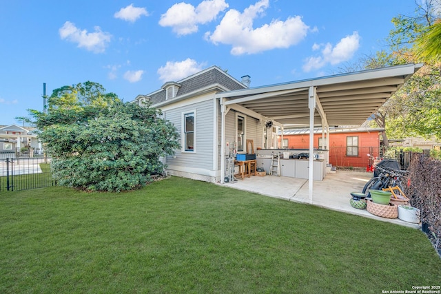 rear view of property with fence, roof with shingles, a lawn, mansard roof, and a patio area