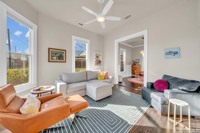 living room with visible vents, wood finished floors, and a ceiling fan