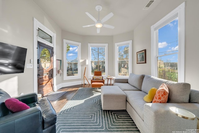 living area featuring visible vents, baseboards, wood finished floors, and a ceiling fan