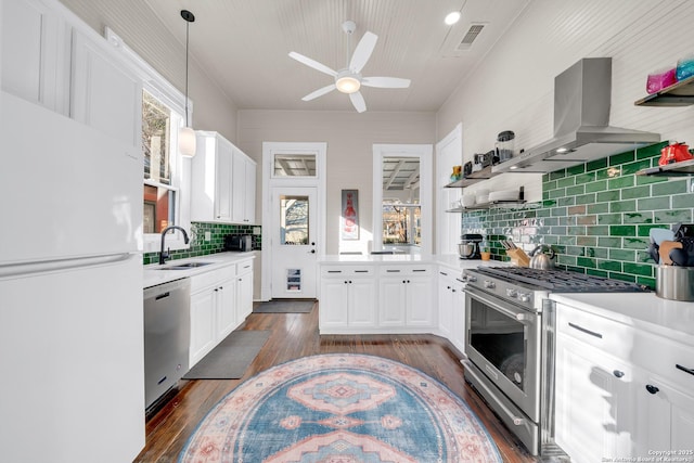 kitchen with island exhaust hood, dark wood-style floors, stainless steel appliances, white cabinets, and light countertops