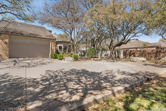 view of yard featuring a garage, driveway, and fence