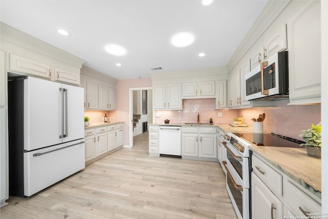 kitchen with white appliances, recessed lighting, a sink, light wood-type flooring, and backsplash