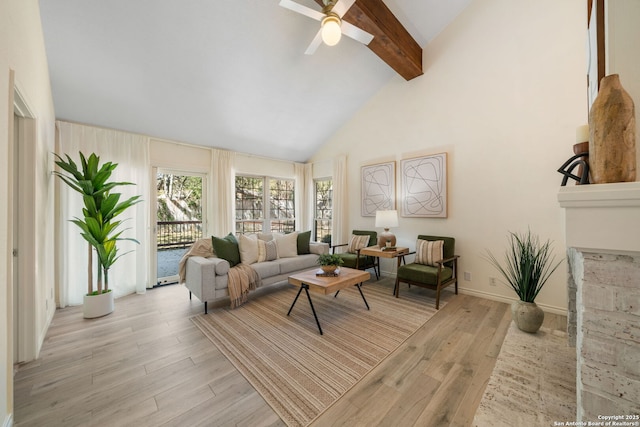 living room with beam ceiling, high vaulted ceiling, a ceiling fan, light wood-style floors, and baseboards