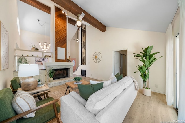 living room with beam ceiling, high vaulted ceiling, a fireplace with raised hearth, wood finished floors, and baseboards