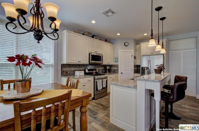 kitchen with visible vents, a sink, dark wood-style floors, stainless steel appliances, and decorative backsplash