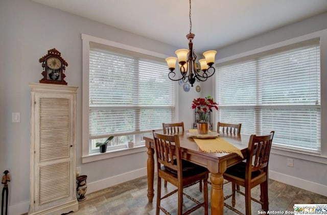 dining space with an inviting chandelier, baseboards, and wood finished floors