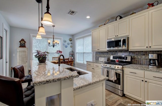 kitchen featuring visible vents, backsplash, stainless steel appliances, and a sink