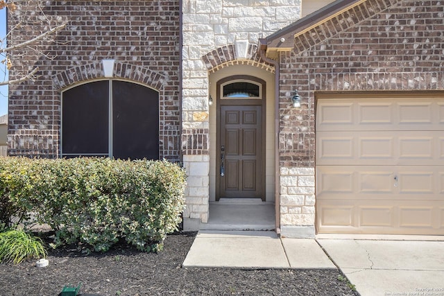 entrance to property with brick siding and a garage